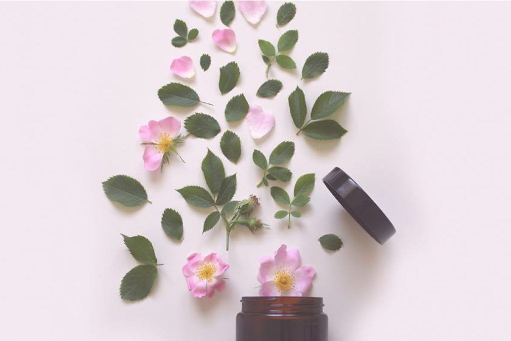 Pote de crema con flores rosas y hojas